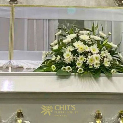 Elegant funeral casket flower arrangement with white chrysanthemums and mums symbolizing peace and remembrance, handcrafted by Chits Floral House.