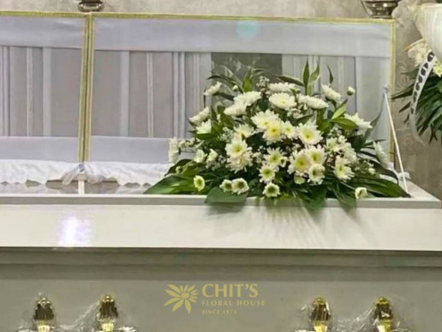 Elegant funeral casket flower arrangement with white chrysanthemums and mums symbolizing peace and remembrance, handcrafted by Chits Floral House.