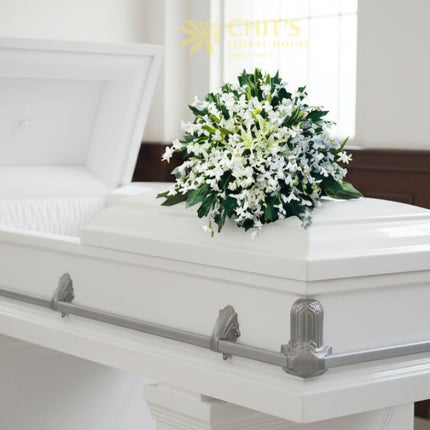 Elegant funeral casket flower arrangement featuring pure white orchids symbolizing peace, remembrance, and eternal love. Handcrafted by Chits Floral House.