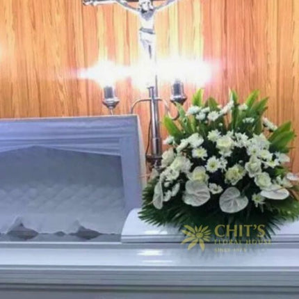 Elegant white funeral casket flower arrangement featuring roses, anthuriums, and chrysanthemums symbolizing purity and eternal rest.