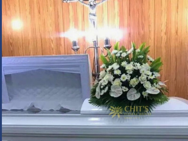Elegant white funeral casket flower arrangement featuring roses, anthuriums, and chrysanthemums symbolizing purity and eternal rest.
