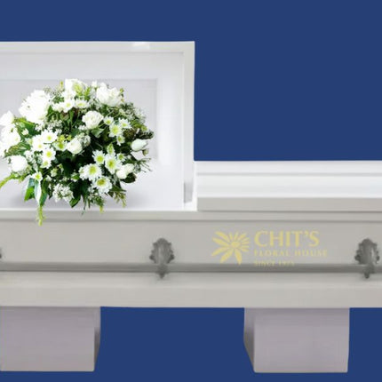 Elegant white casket flower arrangement featuring roses, chrysanthemums, and baby’s breath symbolizing peace and eternal rest.