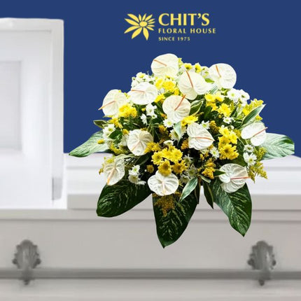 Sunlit Solace funeral casket flower arrangement with white and yellow mums and anthuriums by Chits Floral House