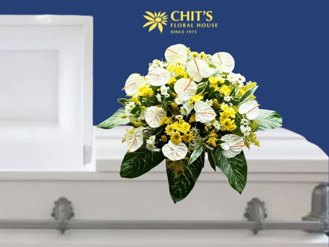 Sunlit Solace funeral casket flower arrangement with white and yellow mums and anthuriums by Chits Floral House