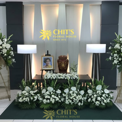 Urn funeral floral setup with white mums and anthuriums